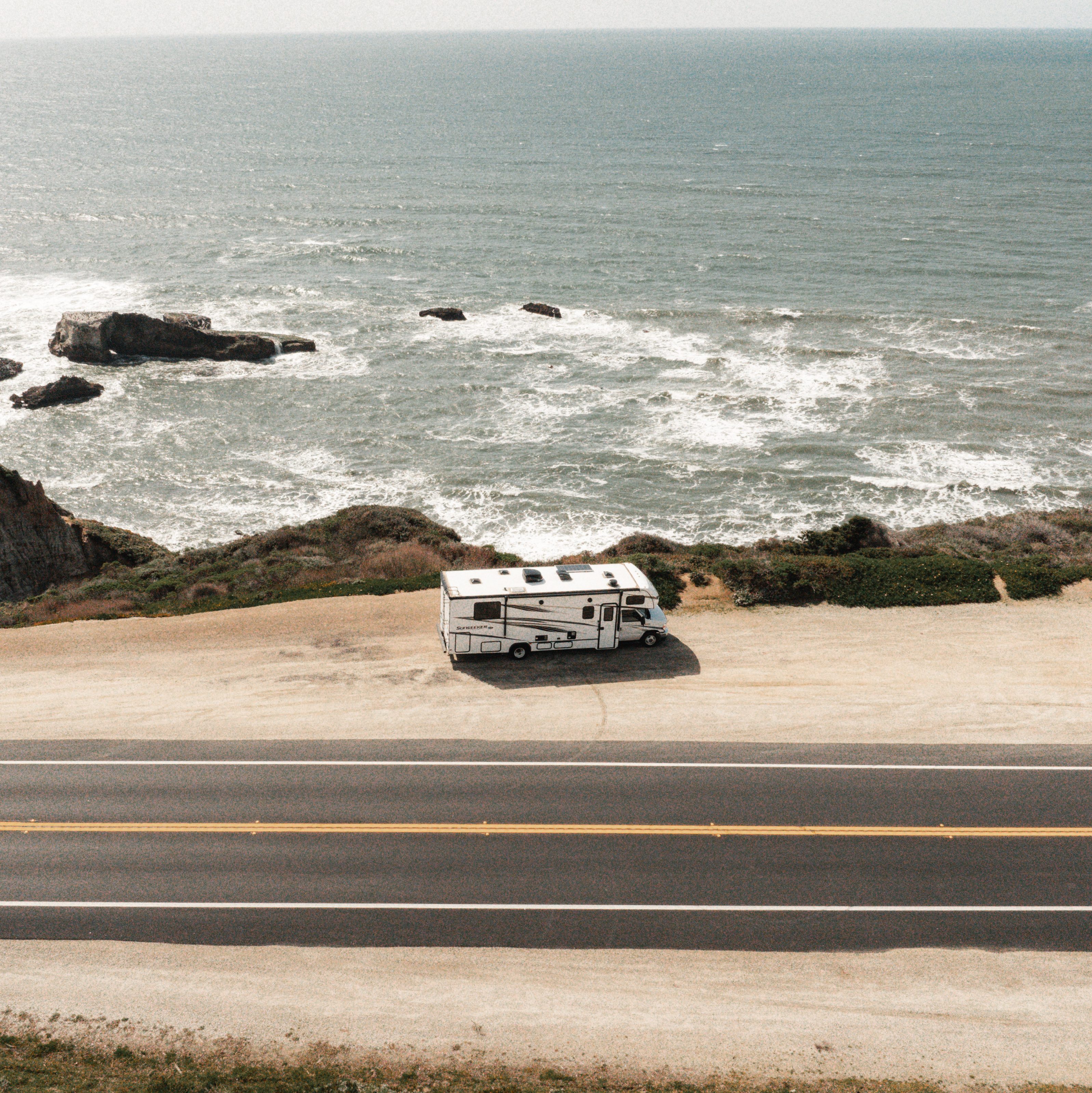 RV parked on side of road near ocean